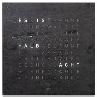 Die QLOCKTWO EARTH 90 in METAMORPHITE ist in der Front Ansicht. Ein stilvolles Kunstwerk wo jedes Exemplar ist ein Unikat, gefertigt auf echtem Stein.   Und das ikonische Buchstabenraster, das die Uhrzeit in Worten darstellt.